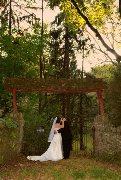 Wedding photographer poses the bride and groom at an antique fence.