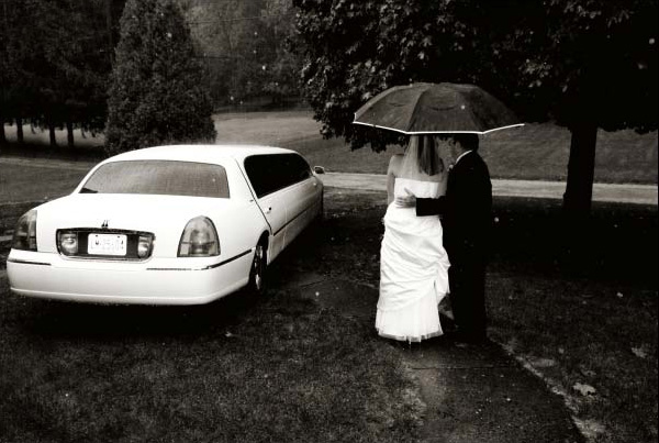 The wedding photographer captures father escorting bride to the wedding in the rain.