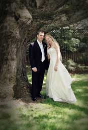 formal portrait of bride and groom under a tree